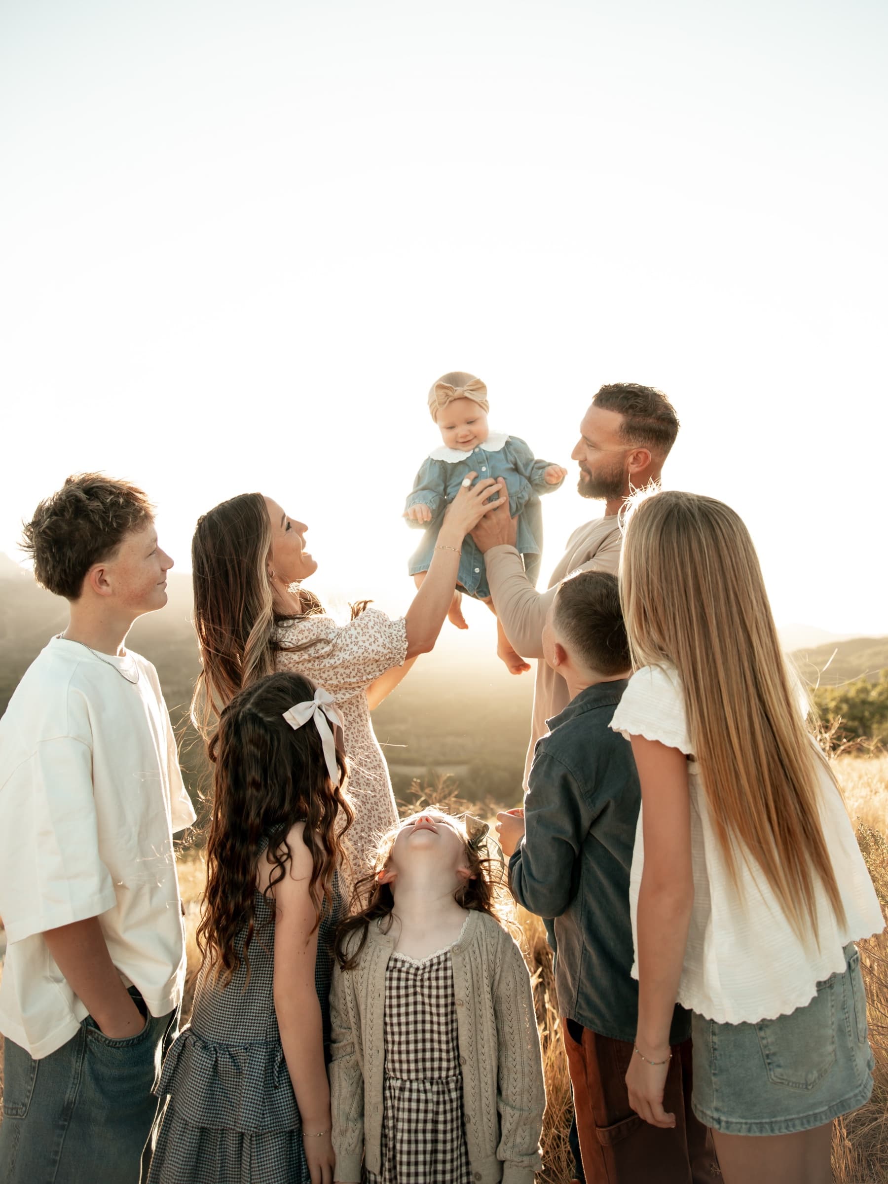 A large family gathers in warm evening light.