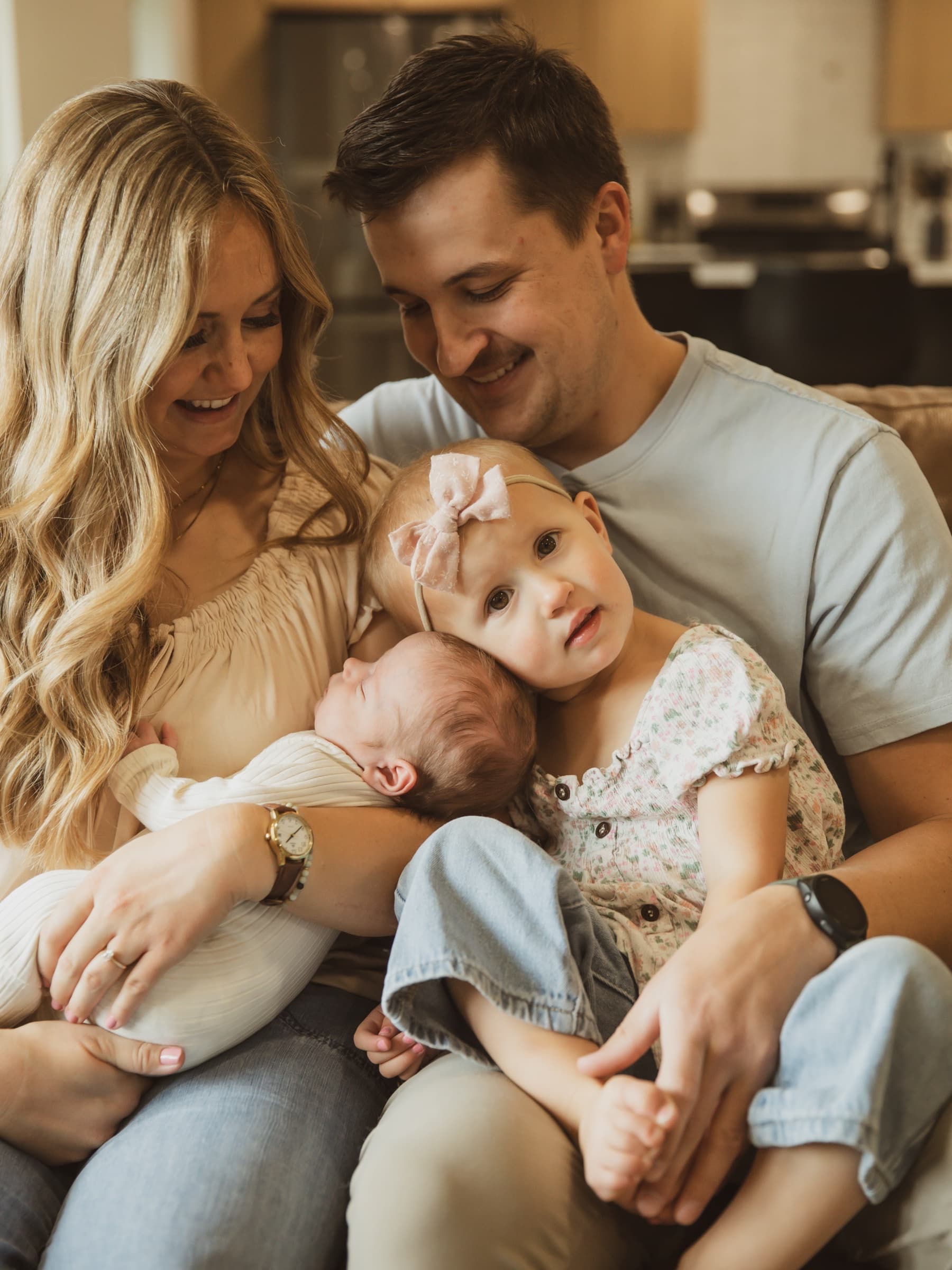 Parents and children settle together on a couch at home.