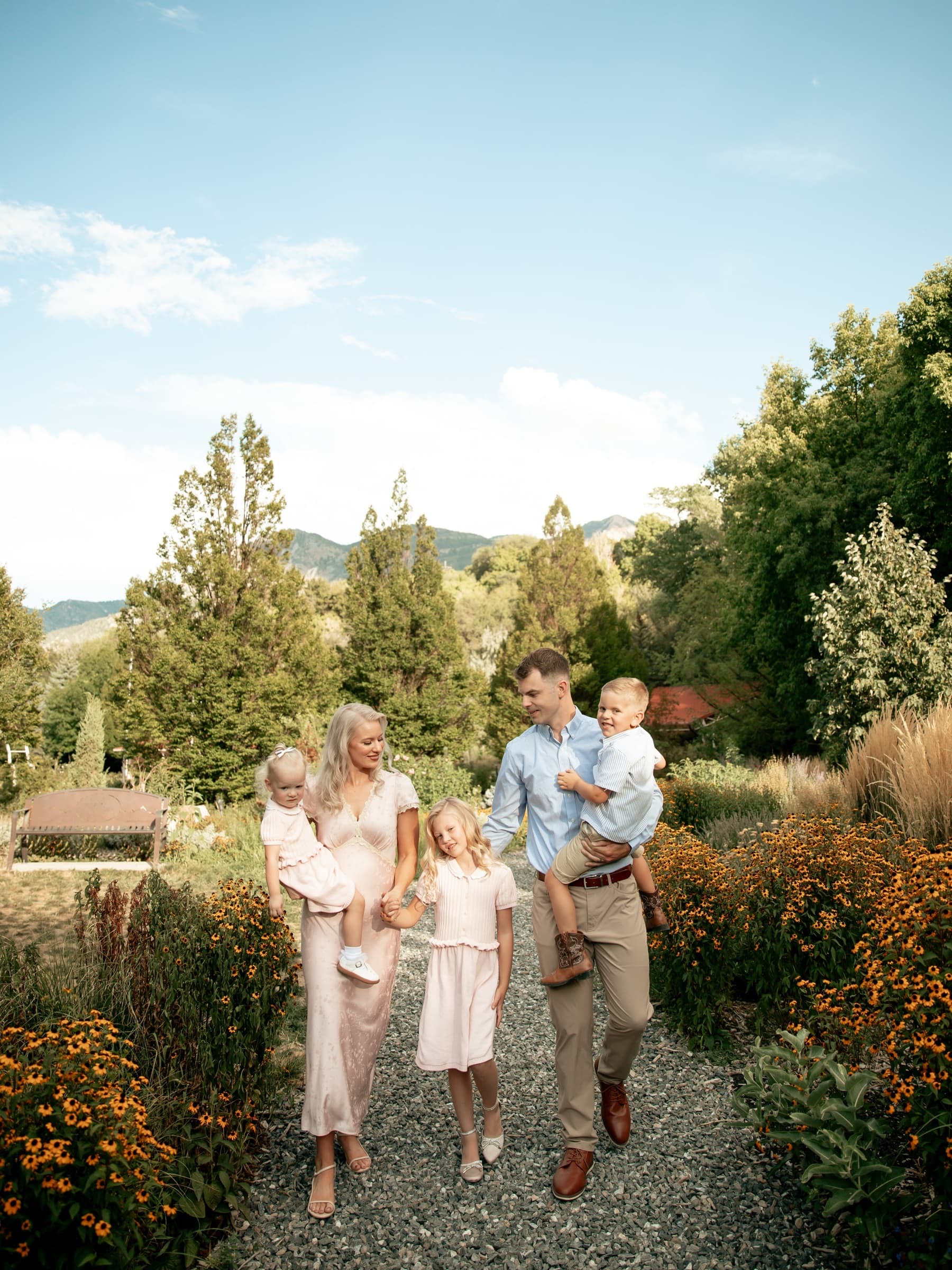 A family walks through a flower garden in soft evening light.