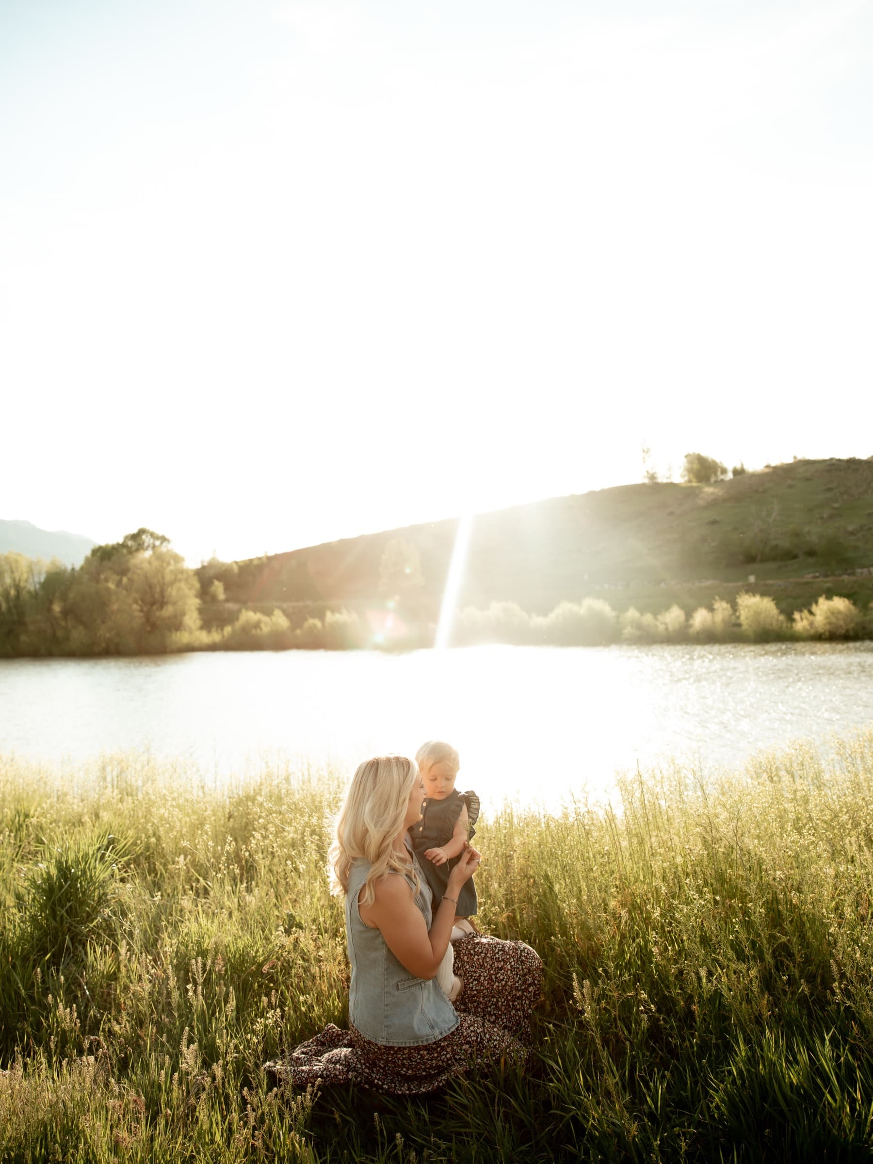A mother holds her child beside a sunlit lake in Northern Utah.