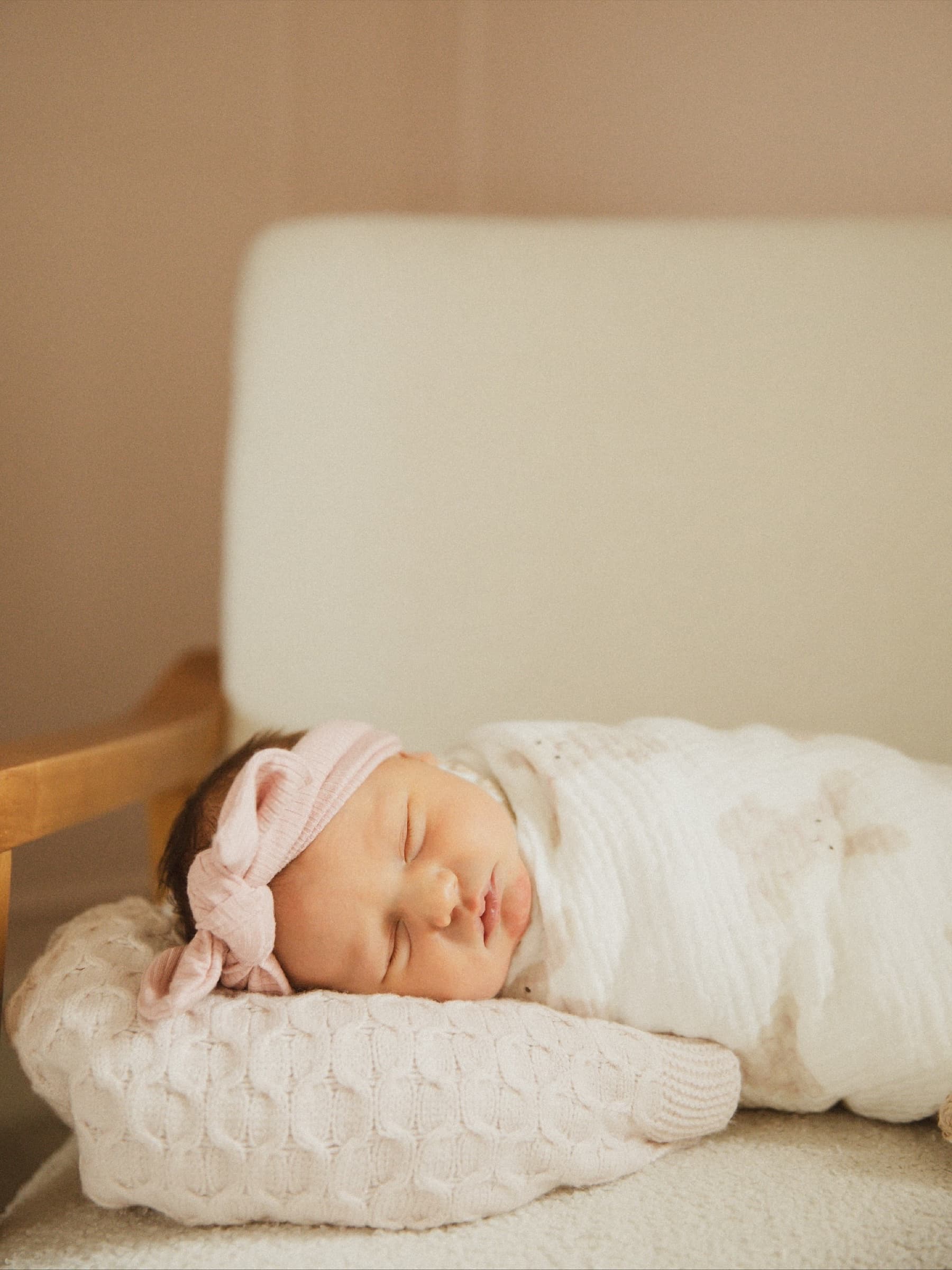A sleeping newborn rests in soft window light.