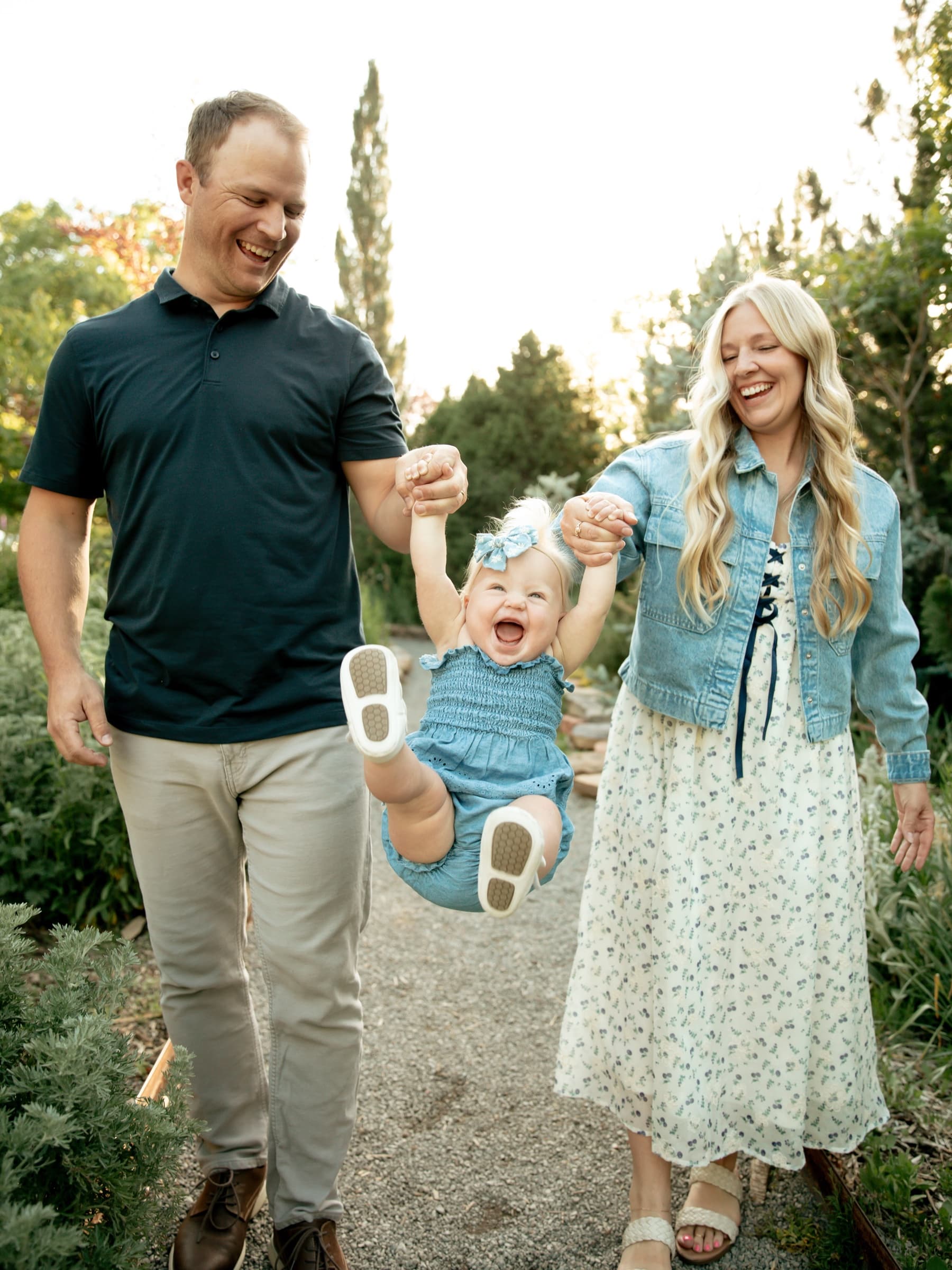 Parents laugh while swinging their toddler between them.